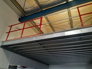 Mezzanine level with red guardrail and silver sliding pallet gate.